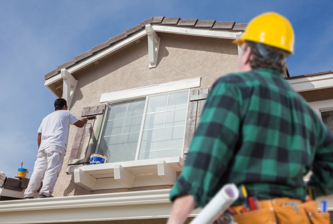 Contractor Overlooking Painter Painting House